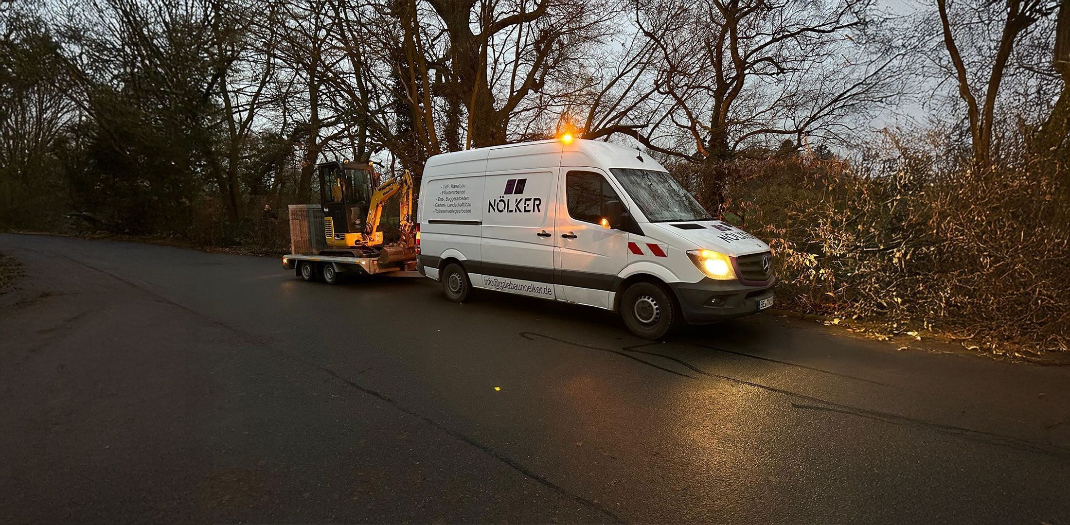 Ein Nölker Transport-Lkw mit einem Bagger auf einem Anhänger in einer ländlichen Umgebung
